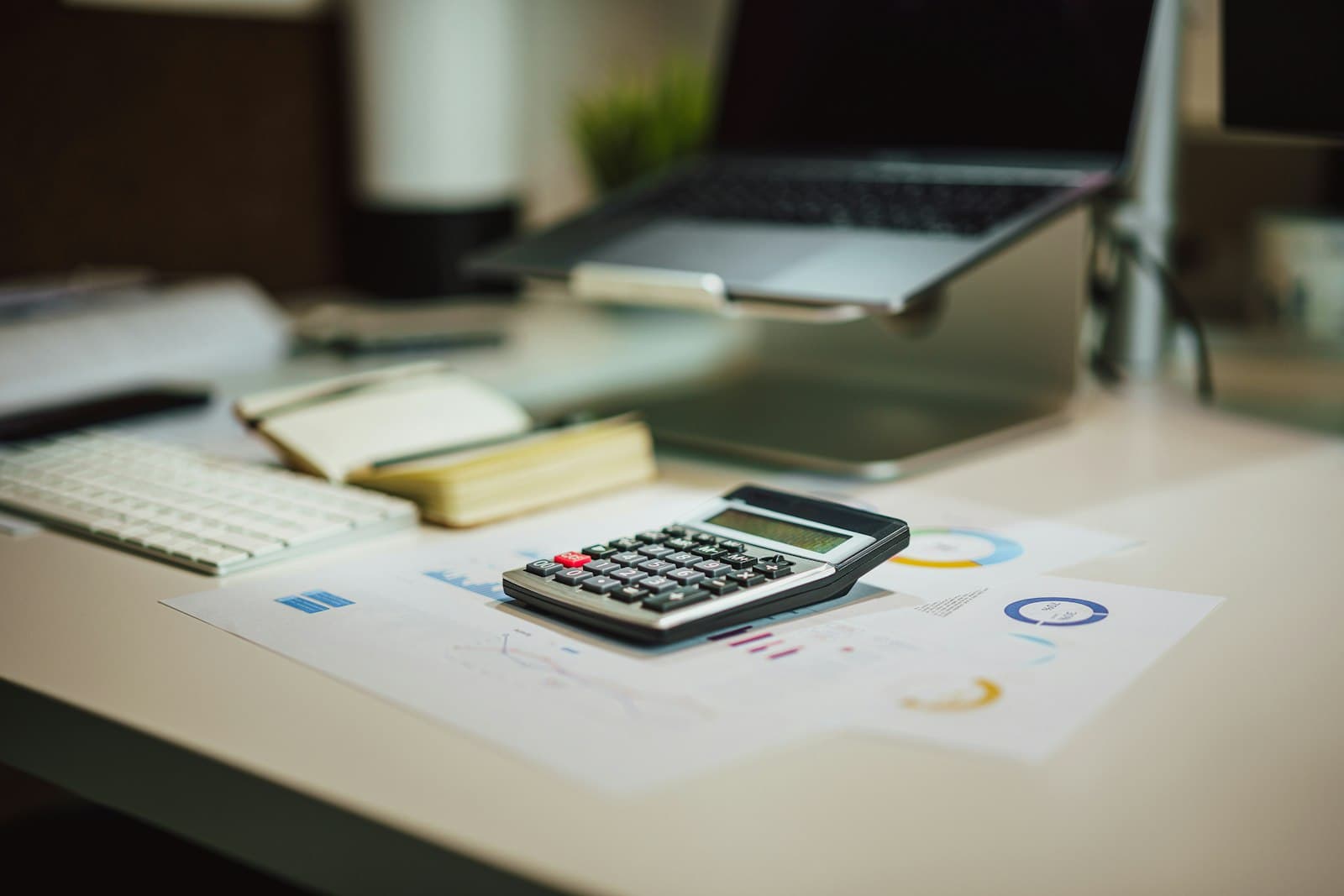 A calculator beside a laptop on a desk